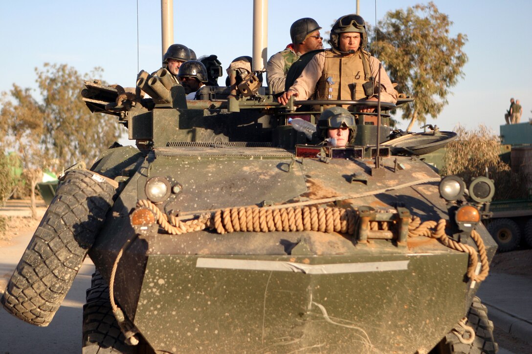 CAMP KOREAN VILLAGE, Iraq (March 8, 2007) -- NFL football players Alge Crumpler, Atlanta Falcons; Shelton Quarles, Tampa Bay Buccaneers; Will Shields, Kansas City Chiefs and Benjamin Watson, New England Patriots ride in a Marine Light Armored Vehicle during a visit to Camp Korean Village, Iraq March 8.  The professional football stars signed autographs and posed for pictures with the Marines and sailors of the 15th Marine Expeditionary Unit (Special Operations Capable).  The players visited several different bases throughout Iraq as part of a tour sponsored by the United Service Organization.  The players were as appreciative of the troops they visited as the troops are for the time the players devoted to visiting Iraq, according to Quarles.  "Everybody has been excited about us being here and been appreciative of us taking our time to come out during the off season.  I'm definitely appreciative of what [the troops] are doing for us, providing our freedom and giving us the opportunity to do what we do," Quarles said..  The 15th MEU (SOC) moved into Rutbah Jan. 20 to provide security and to establish an Iraqi Police force in the city. (U.S. Marine Corps photo by ) (Released)