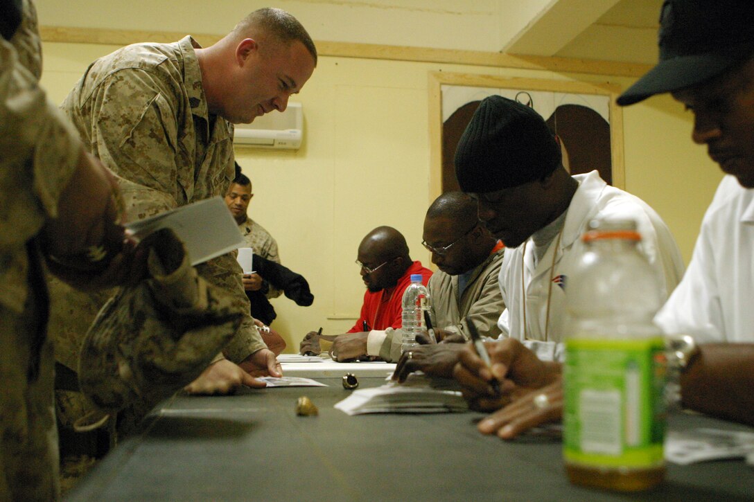 CAMP KOREAN VILLAGE, Iraq (March 8, 2007) -- NFL football players Alge Crumpler, Atlanta Falcons; Shelton Quarles, Tampa Bay Buccaneers; Will Shields, Kansas City Chiefs and Benjamin Watson, New England Patriots sign autographs at the Camp Korean Village, Iraq Morale, Welfare, and Recreation center during a visit to Camp Korean Village, Iraq.  The professional football stars signed autographs and posed for pictures with the Marines and sailors of the 15th Marine Expeditionary Unit (Special Operations Capable).  The players visited several different bases throughout Iraq as part of a tour sponsored by the United Service Organization.  The players were as appreciative of the troops they visited as the troops are for the time the players devoted to visiting Iraq, according to Quarles.  "Everybody has been excited about us being here and been appreciative of us taking our time to come out during the off season.  I'm definitely appreciative of what [the troops] are doing for us, providing our freedom and giving us the opportunity to do what we do," Quarles said..  The 15th MEU (SOC) moved into Rutbah Jan. 20 to provide security and to establish an Iraqi Police force in the city. (U.S. Marine Corps photo by Lance Cpl. Timothy Parish) (Released)
