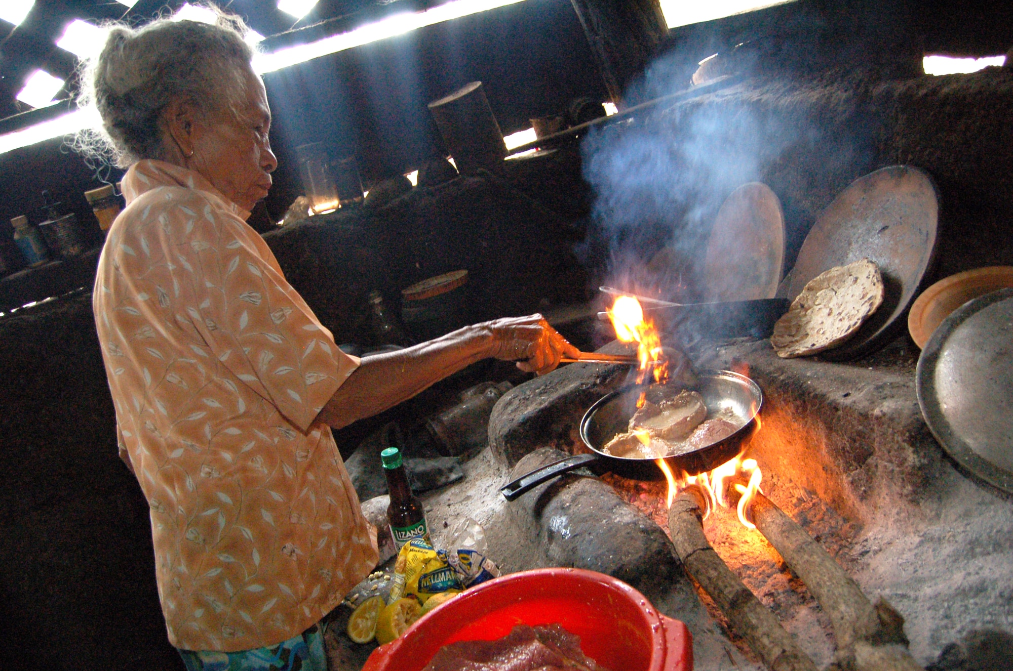 Luisa Palacio-Cortez, the 83-year-old woman who lives in a two-room house next to Camp Red Horse, cooks beef for her family's evening meal. Beef is a rarity for her and her family. She said they mostly live on beans, rice, tortillas and sometimes one of the chickens that run around their property. (U.S. Air Force photo/Senior Airman Jacque Lickteig)