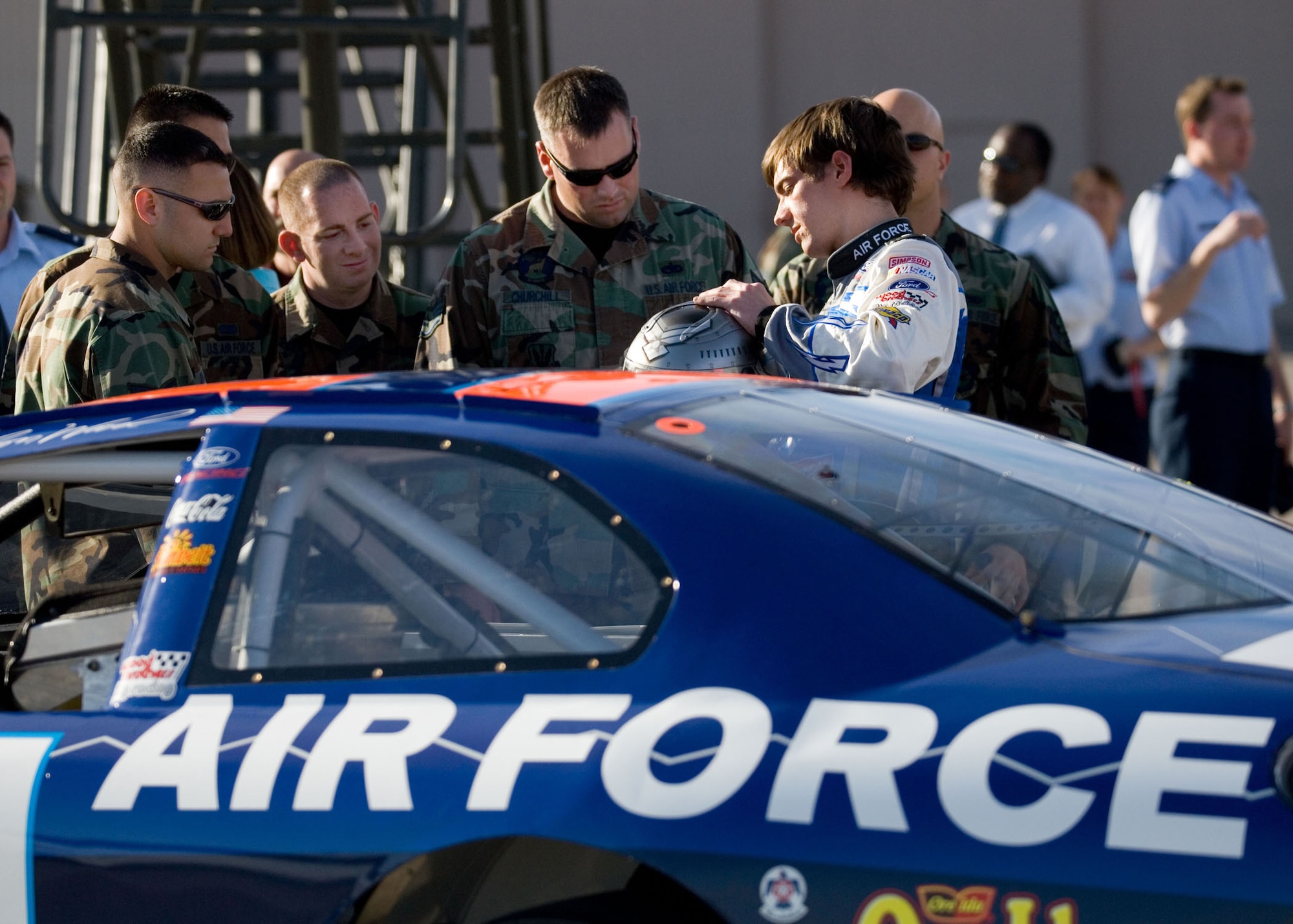 Jon Wood, driver of the Air Force car, shows his racing helmet to crew chiefs from the 57th Wing, Nellis Air Force Base, Nev., March 8.  Wood is at Nellis visiting Airmen before his NASCAR Nextel Cup UAW Daimler-Chrysler 400 race March 10. (U.S. Air Force Photo/Master Sgt. Robert W. Valenca)      