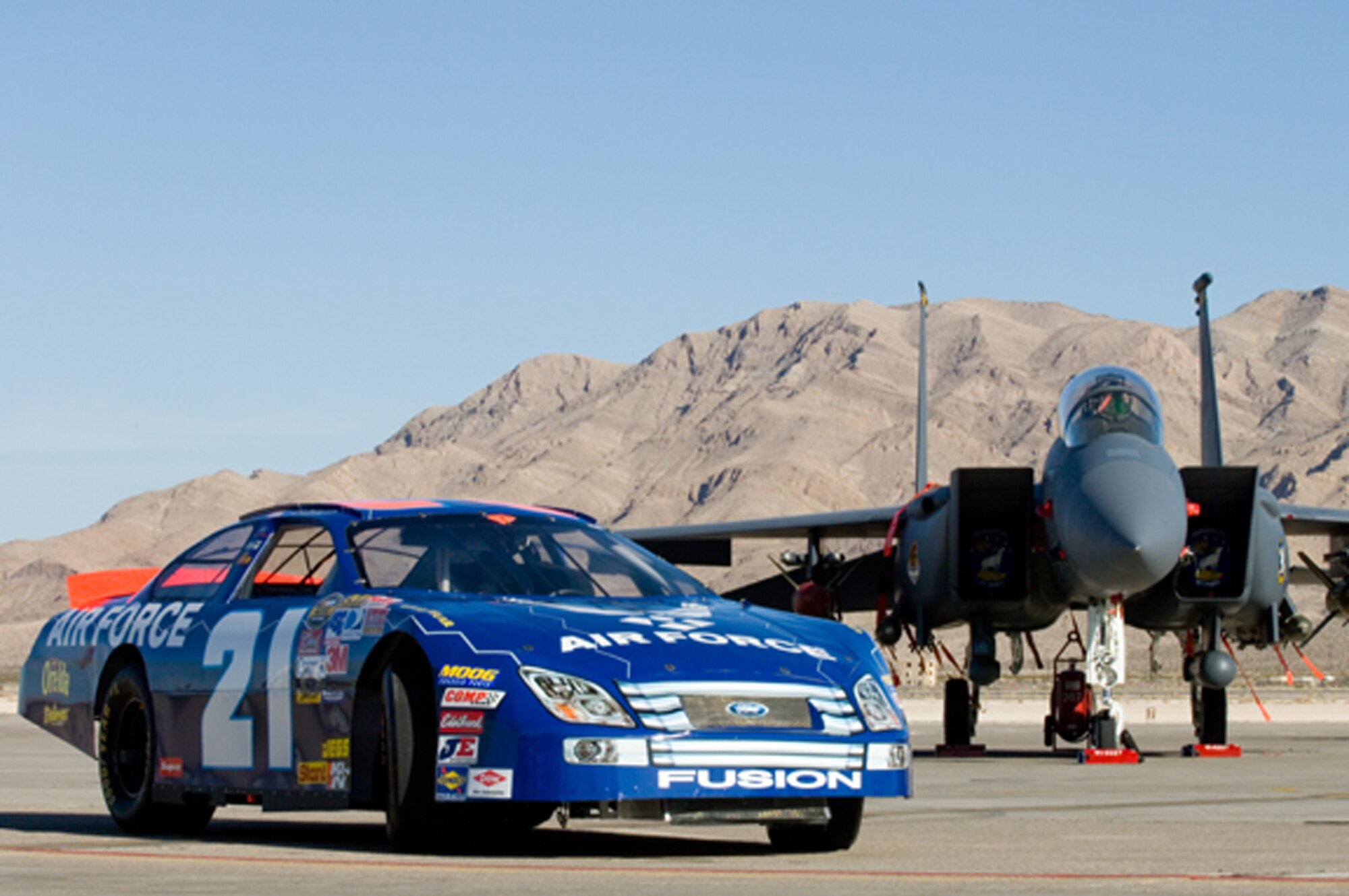 The Air Force-sponsored Nextel Cup car shares the Nellis Air Force Base, Nev., flightline with another Air Force powerhouse, the F-15 Eagle, on March 8.  The car, driven by Jon Wood, was brought to Nellis so Airmen could have a close-up look before its NASCAR Nextel Cup UAW Daimler-Chrysler 400 race on Sunday, March 10. (U.S. Air Force Photo by Master Sgt Robert W. Valenca)    
