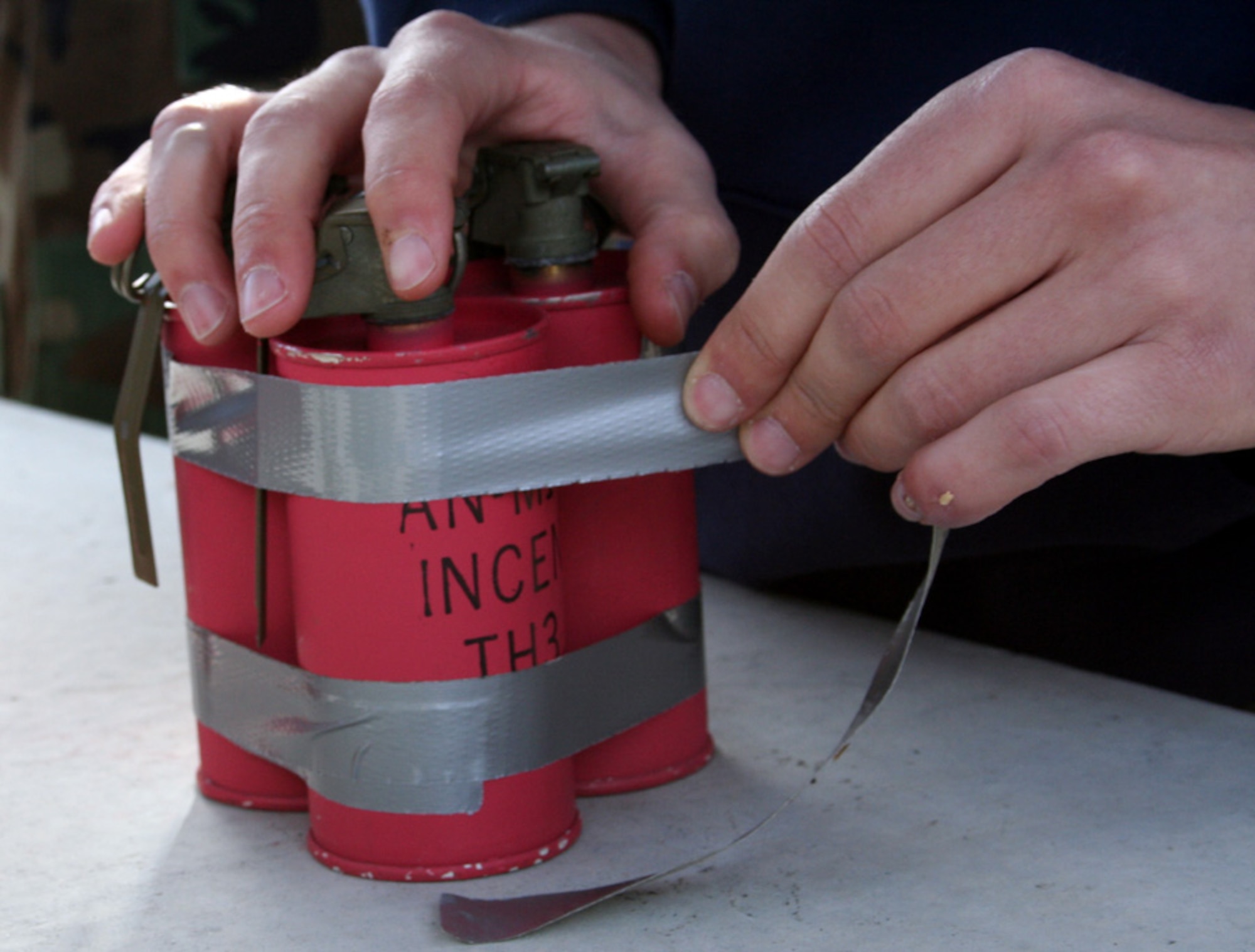 An EOD apprentice prepares three incendiary grenades for an EOD procedure. (U.S. Air Force photo by Staff Sgt. Angela Shepherd)