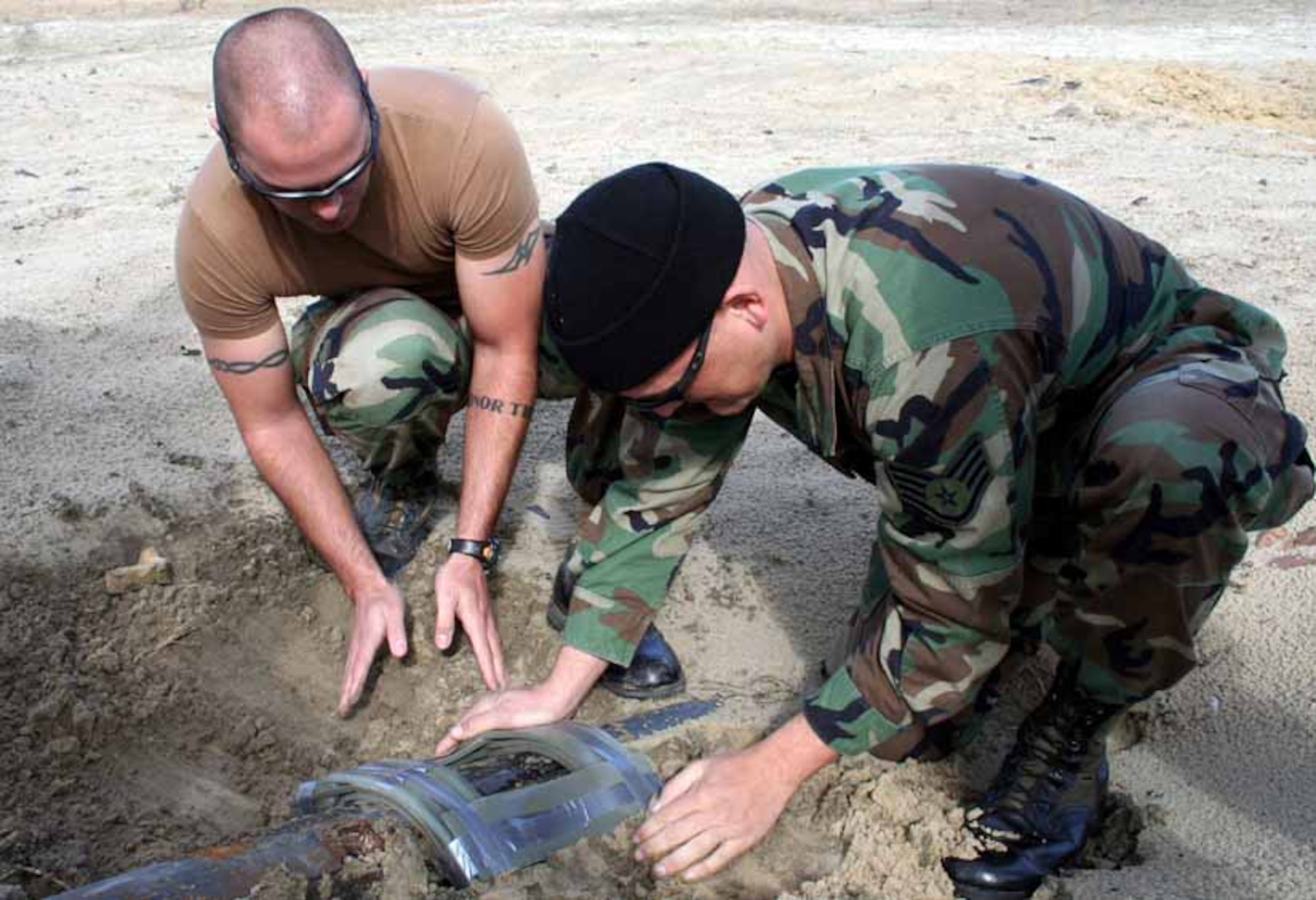 Staff Sgts. Joseph Deslauriers (left) and Joseph Gorney prepare the area around an old gun barrel for a detonation. (U.S. Air Force photo by Staff Sgt. Angela Shepherd)