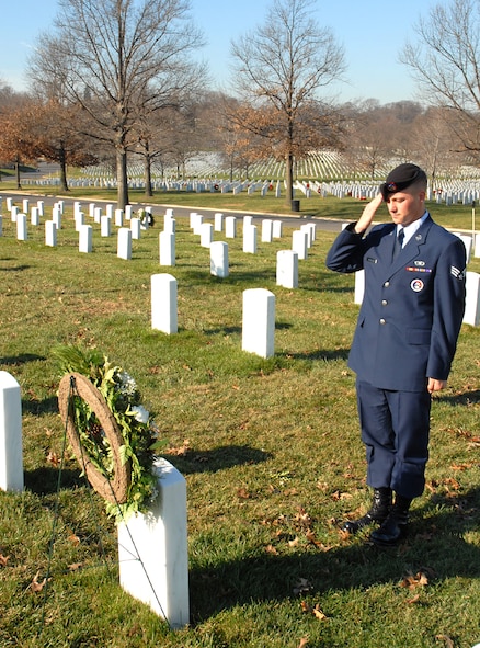 Senior Airman Dustin Woodford, U.S. Air Force Honor Guard, salutes his fathers grave site at Arlington National Cemetery.
