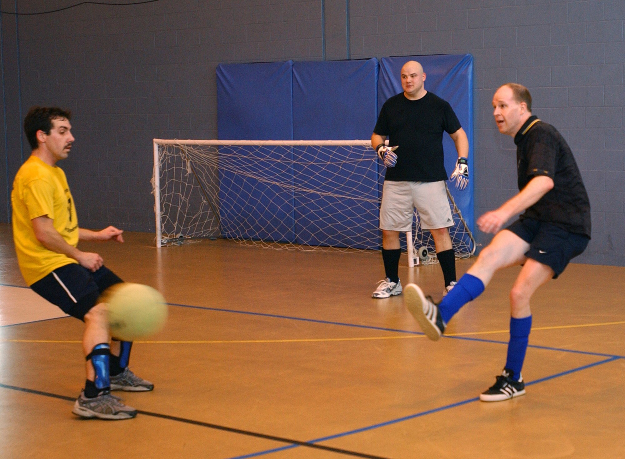 Gary Butcher, 100th Services Squadron, right, clears the ball out of defense past Ben Murray, 100th Air Refueling Wing, with Joshua Drobil in goal for 100 SVS. (U.S. Air Force photo by Airman Brad Smith)                                               