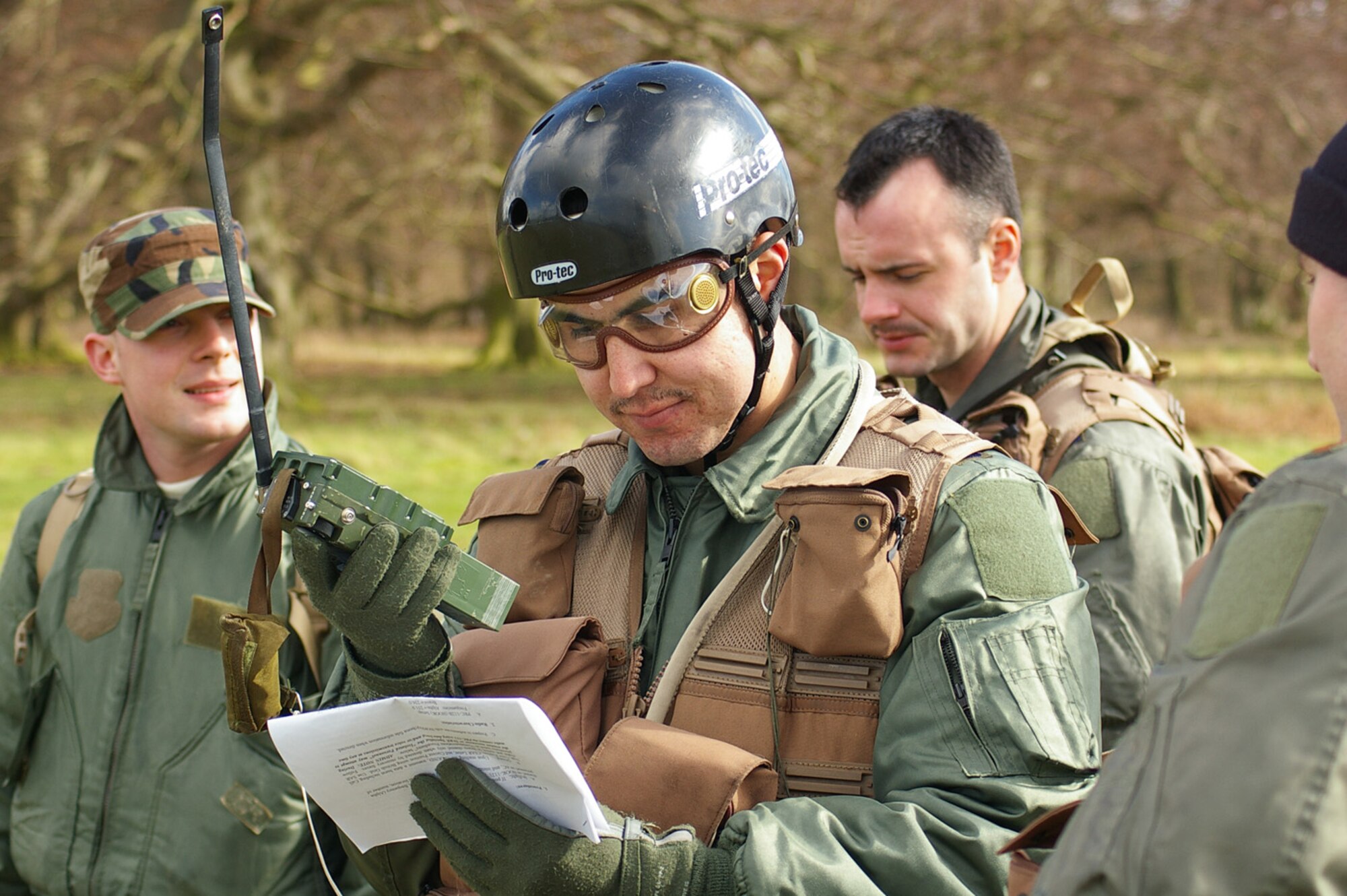 1st Lt. Jeramie Castellanos, 351st Air Refueling Squadron, center, checks information while talking on a PRC-112 radio during a mock rescue scenario, during which members from the 100th Air Refueling Wing  worked with aircrews from the 352nd Special Operations Group to simulate a rescue mission involving a crash landing March 6 at the Stanta training range near Thetford, England. (U.S. Air Force photo by Karen Abeyasekere)