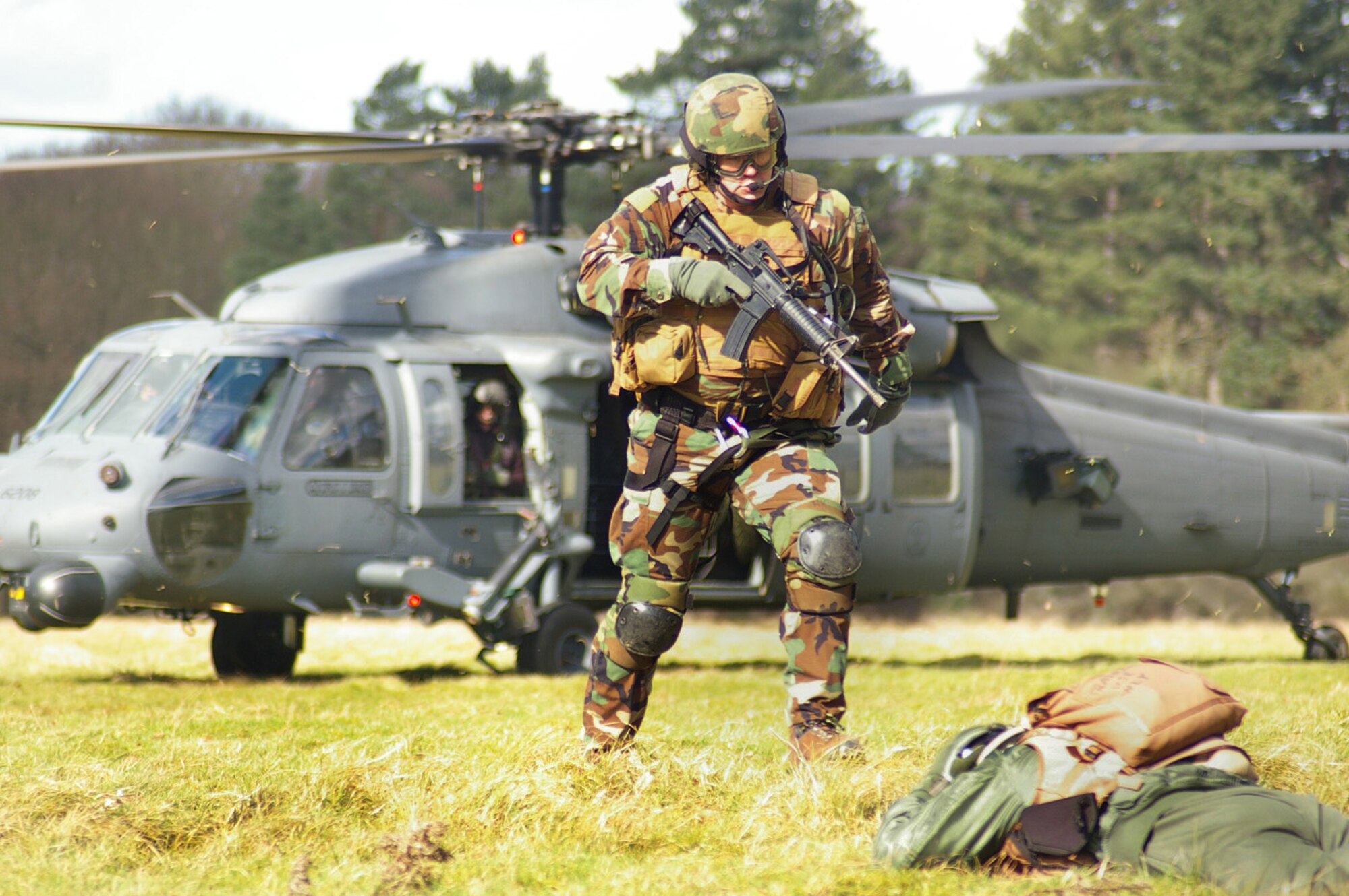 A member from the 56th Rescue Squadron, from RAF Lakenheath, stands over 1st lt. Jeramie Castellanos, 351st ARS, before taking him aboard a Pave Hawk helicopter during a mock rescue as part of a combat survival training event March 6 at Stanta training range near Thetford, England. (U.S. Air Force photo by Karen Abeyasekere)