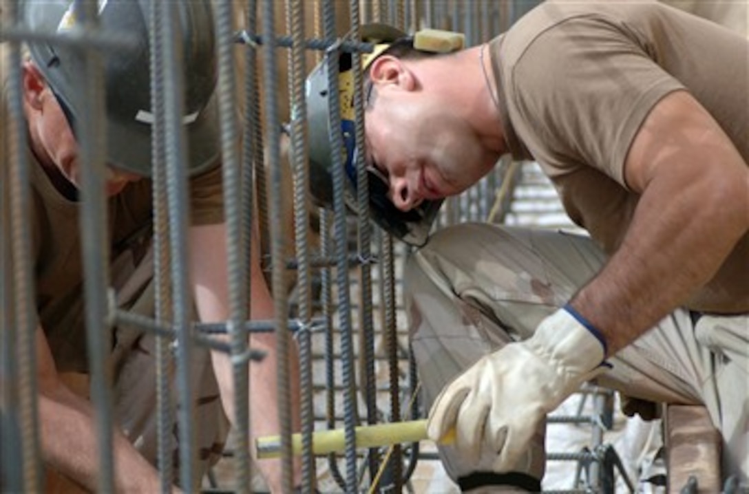 U.S. Navy Petty Officer 3rd Class James Pelitier measures rebar spacing to ensure accuracy while Utilitiesman Greg Frost readjusts rebar ties as needed before the crew pours concrete for a new ramp being installed at the post office on Camp Arifjan, Kuwait, March 7, 2007.