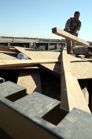 HABBINIYAH, Iraq - An Iraqi soldier loads a piece of wood on the back of his truck here March 11. The 1st Motor Transportation Regiment, 1st Iraqi Army Division provides transportation support for the division as well as many other logistical capabilities to support the Iraqi soldiers on the ground.