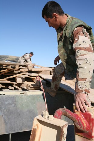 HABBINIYAH, Iraq - An Iraqi soldier climbs on the back of his truck here March 11. The 1st Motor Transportation Regiment, 1st Iraqi Army Division provides transportation support for the division as well as many other logistical capabilities to support the Iraqi soldiers on the ground.