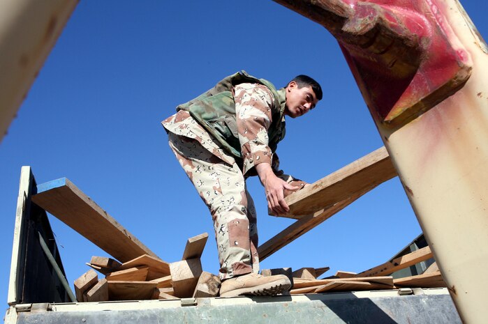HABBINIYAH, Iraq - An Iraqi soldier loads a piece of wood on the back of his truck here March 11. The 1st Motor Transportation Regiment, 1st Iraqi Army Division provides transportation support for the division as well as many other logistical capabilities to support the Iraqi soldiers on the ground.