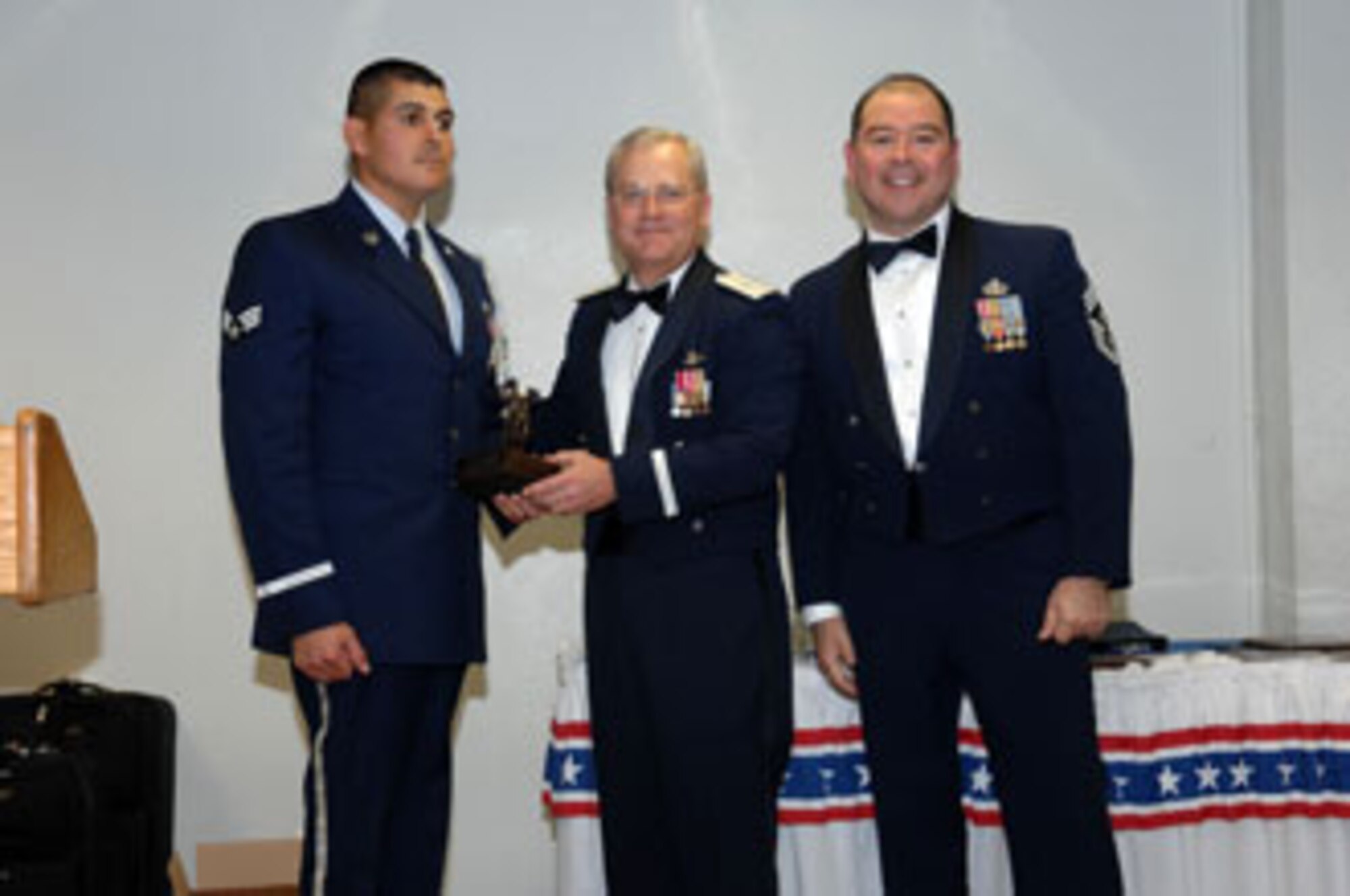 Brig. Gen. James L. Melin, 452nd AMW commander, presents the Honor Guard member of the Year award to Senior Amn. Eduardo Cervantes, 163 CS.  Also congratulating Senior Amn. Cervantes is 452nd AMW Command Chief Master Sgt. Agustin Huerta, right. The 452d Air Mobility Wing's 13th Annual Awards Banquet recognized the men and women in the wing who have made a difference in 2006. The banquet was held at March Air Reserve Base in February.  (U.S. Air Force photo by 4th Combat Camera)