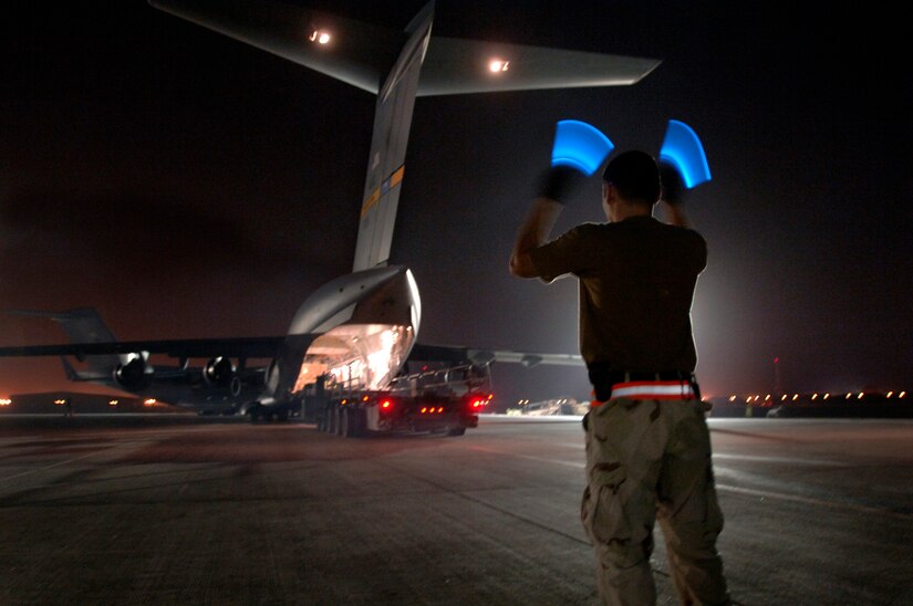Airman 1st Class Arnold Peña marshals out an aircraft loader after loading pallets of bombs onto a C-17 Globemaster III. (U.S. Air Force photo/Tech. Sgt. Cecilio Ricardo Jr.) 