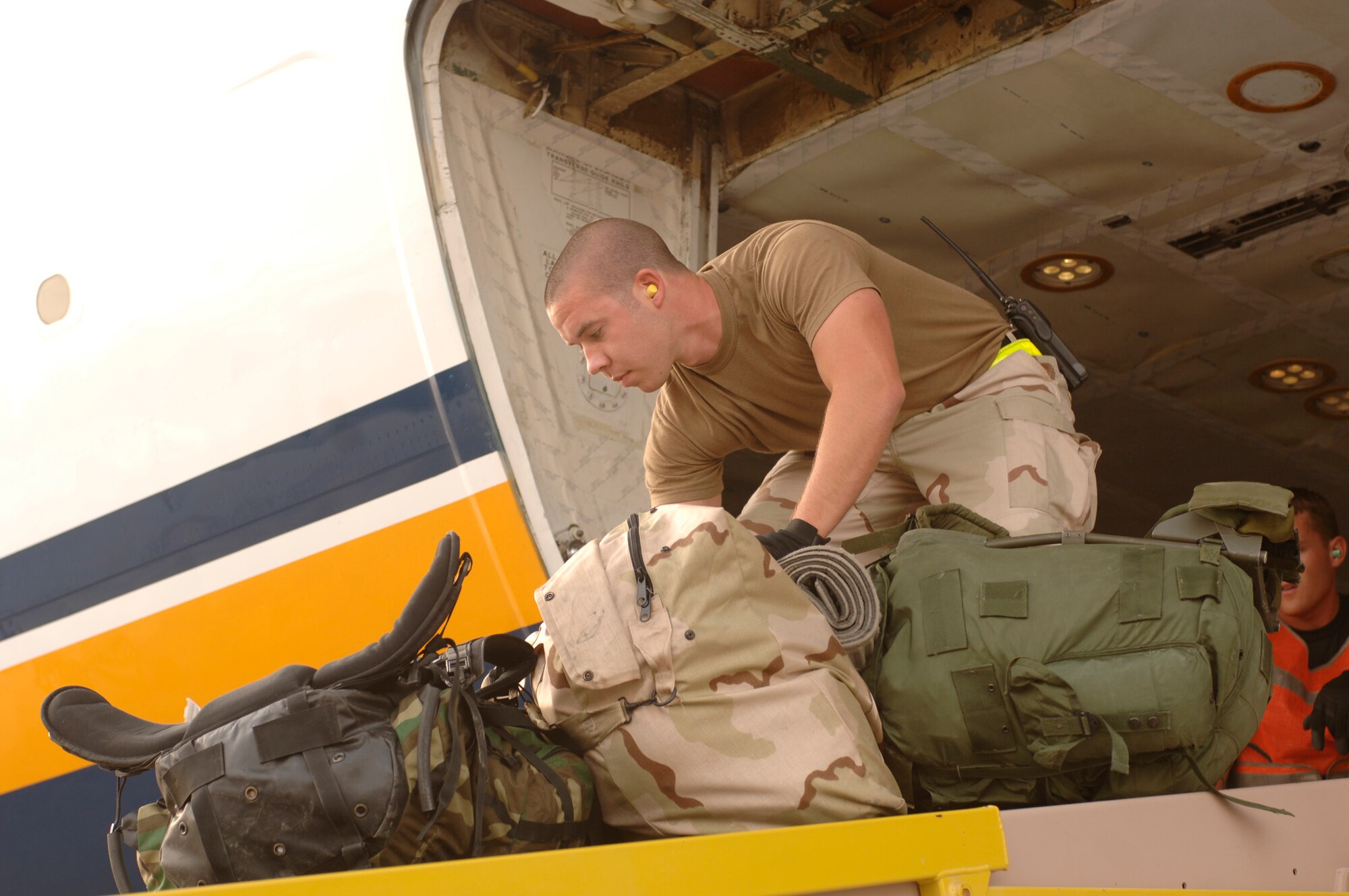 Airman 1st Class Mark Hedge, 8th Expeditionary Air Mobility Squadron air transportation specialist, unloads baggage from a commercial aircraft. Airmen from the squadron processed approximately 257,000 servicemembers, Coalition partners and federal contractors for travel in 2006. (U.S. Air Force photo by Staff Sgt. David Miller)