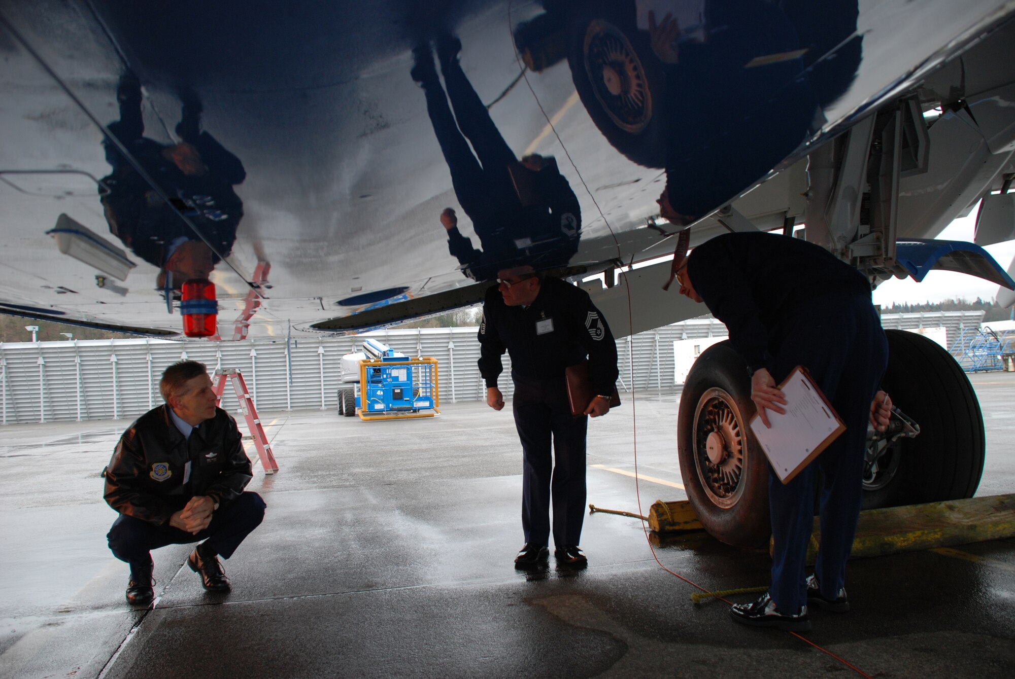Pilots and maintenance members check the belly of the C-40C plane before taking off.  The 932nd Airlift Wing flies both C-9C and C-40C planes.