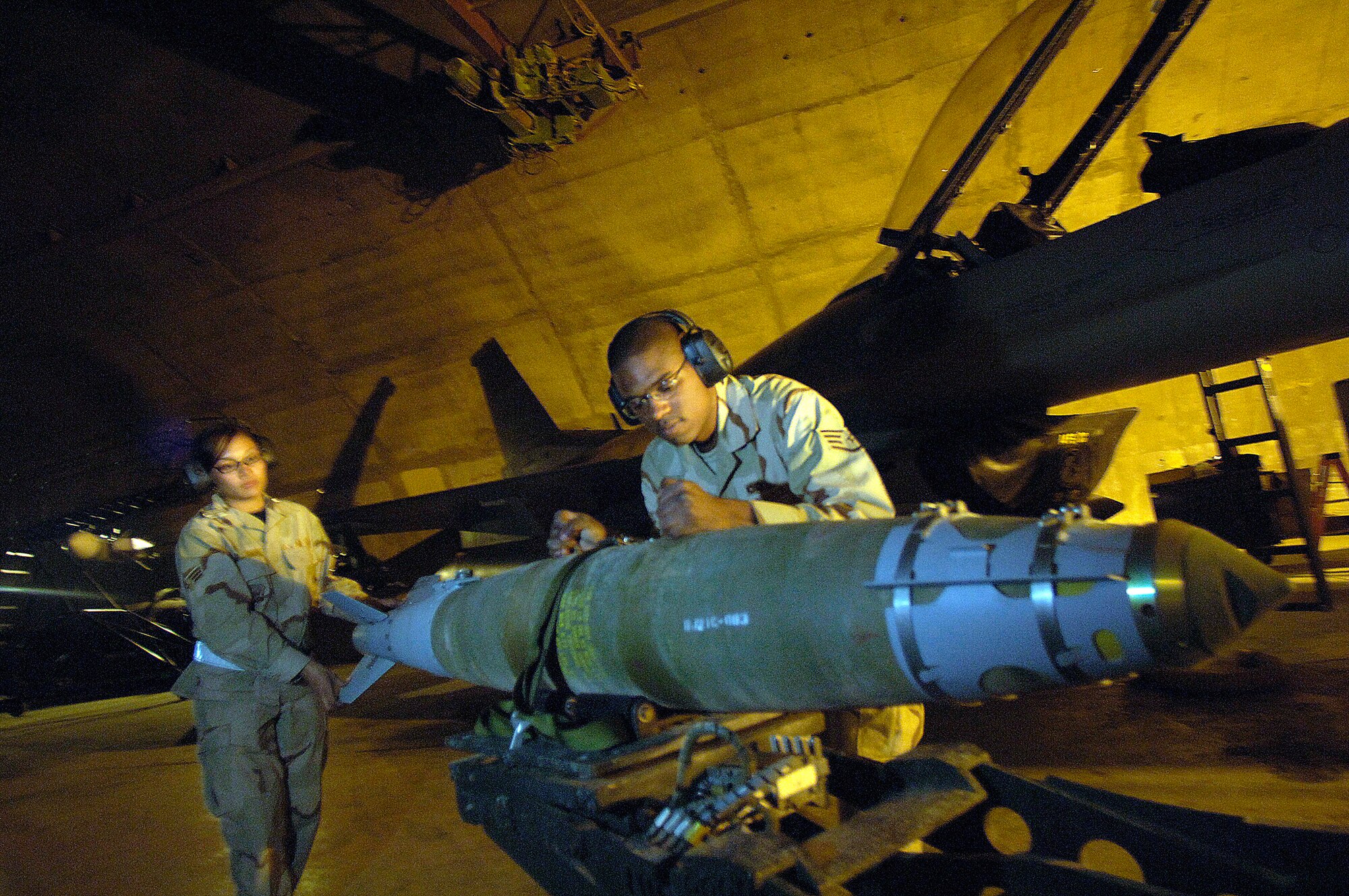 Staff Sgt. Christopher Curry and Senior Airman Roseanne Williams prepare to load munitions on an F-16 Fighting Falcon March 4 at Balad Air Base, Iraq. The Airmen are assigned to the 332nd Expeditionary Aircraft Maintenance Squadron. (U.S. Air Force photo/Airman 1st Class Nathan Doza)
