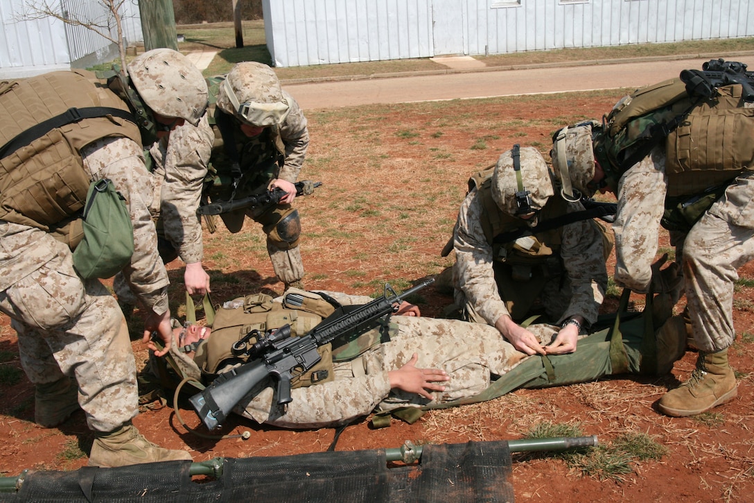 Marines from Company G, 2nd Battalion, 25th Marine Regiment, transfer one of their comrades from a collapsible litter to a poleless litter to begin the second leg of a litter carry relay race at Camp Upshur March 11.