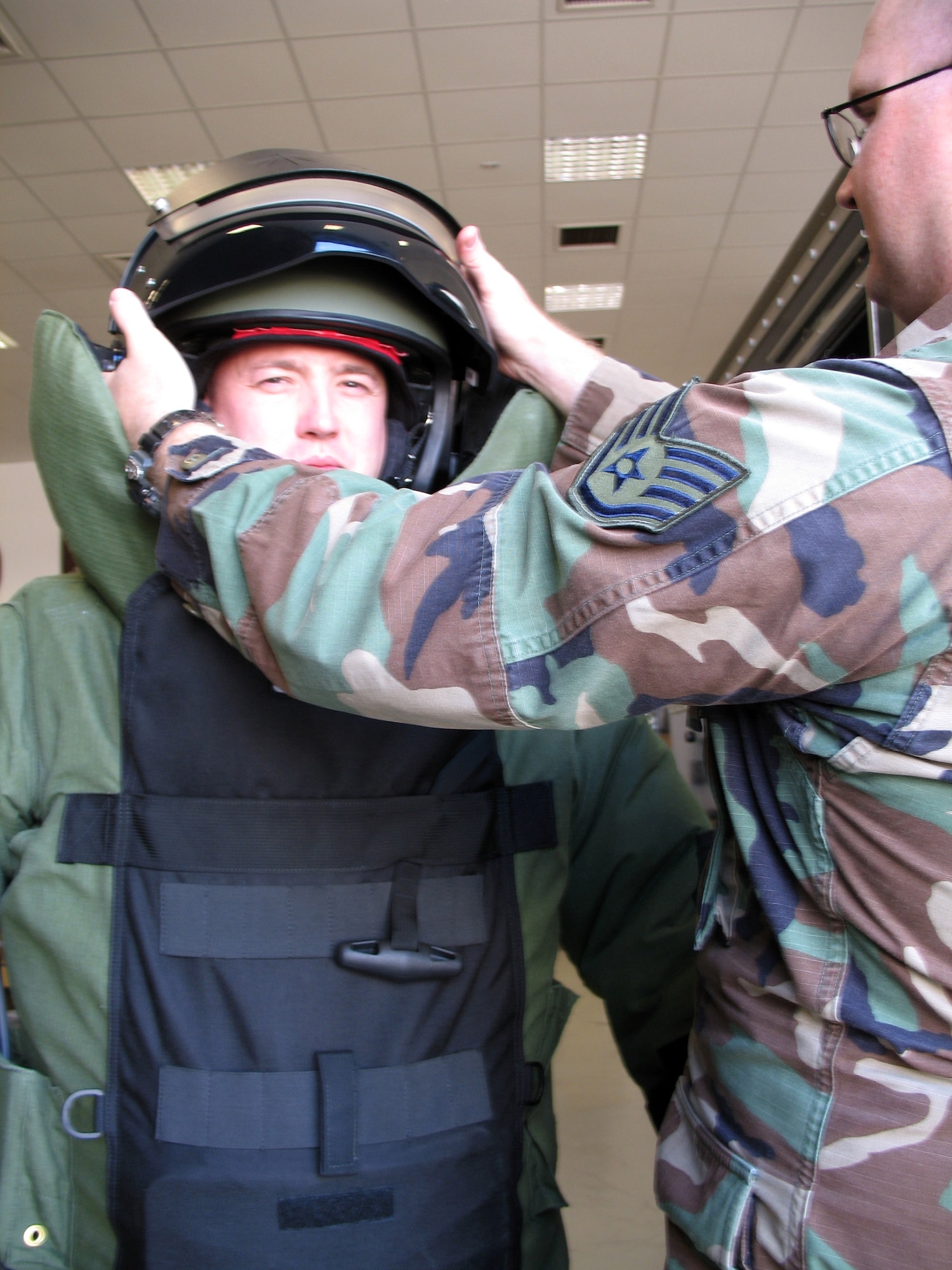 Staff Sgt. Kristoffer Solesbee (right) helps Staff Sgt. Edward Albietz with his bomb suit helmet March 12 in Iraq. The helmet is made of ballistic glass to help shield explosive ordnance members from a bomb blast and fragmentation. (U.S. Air Force photo)