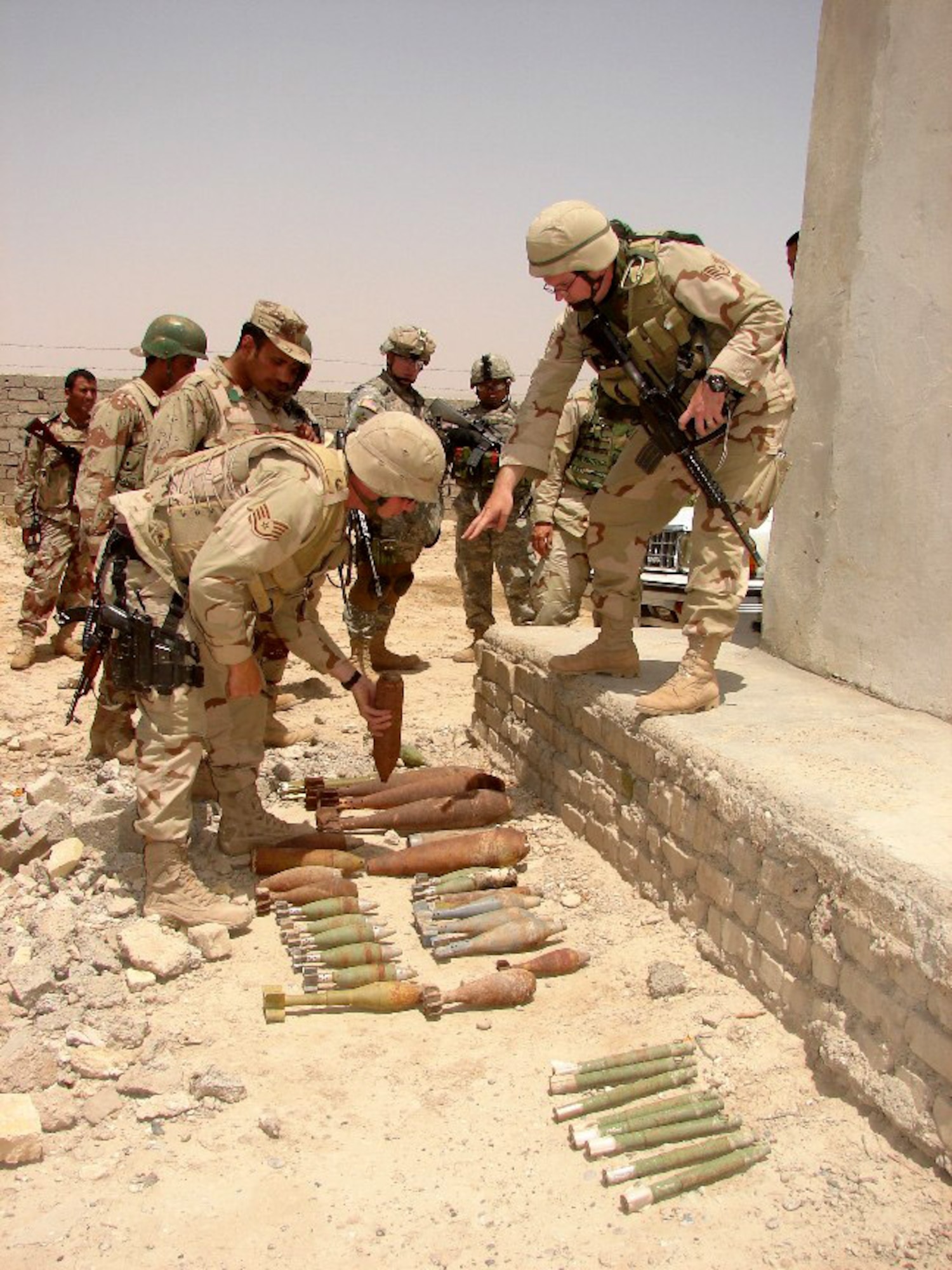 Staff Sgt. Kristoffer Solesbee (right) describes identification features and safety concerns of various unexploded ordnance as Staff Sgt. Christopher Stoup shows the ordnance to Iraqi Army soldiers from the 5th Iraqi Army Bomb Disposal Company March 12 in Iraq. (U.S. Air Force photo) 
