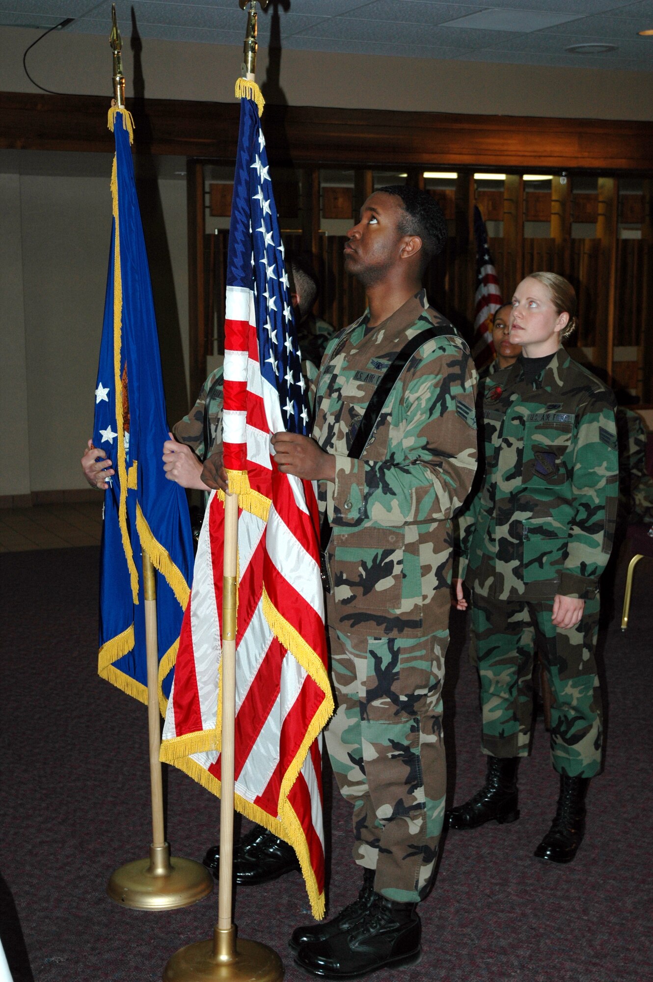 Senior Airman Andrea Isder (right), an instructor with the Air Force Honor Guard, explains proper flag posting procedures March 7 at the former Enlisted Club. Posting the colors are Senior Airmen John Hagens, 2nd Space Warning Squadron, Buckley AFB, and Nicholas Ziegler, 27th Fighter Wing, Canon AFB. (U.S. Air Force photo by Steve Brady)