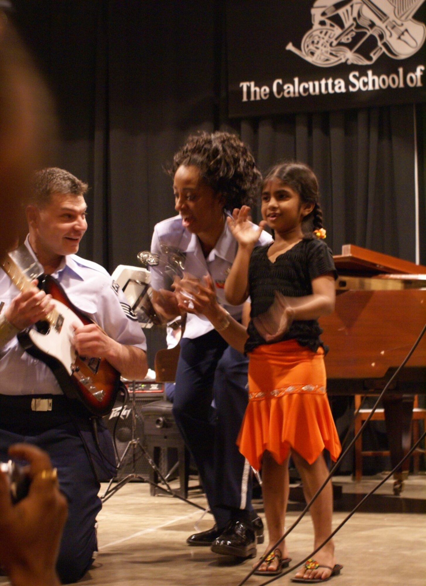 CALCUTTA, India -- Staff Sgts Felita Rowe and Tim Rogers share some American entertainment with a young audience member of the crowd at the Calcutta School of Music.  The Pacific Air Forces rock group, Pacific Trends, was invited by the Chief of Staff of the Indian Air Force to help celebrate the Indian Air Force’s 75th Anniversary.  The IAF will be holding its Platinum Jubilee in New Delhi on 17 and 18 March 2007 and invited Air Force Bands from a wide variety of nations to join the celebration.  In addition to the United States, Sri Lanka, Singapore, Thailand, and Russia have sent Air Force bands to be part of the celebration.