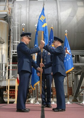 AEDC 704th Test Group Commander Col. Jeff Smith hands the 716th Test Squadron's command flag to Lt. Col. William 'Bill' Hack with the Propulsion Wind Tunnel facility's 16-foot transonic wind tunnel in the background March 12.