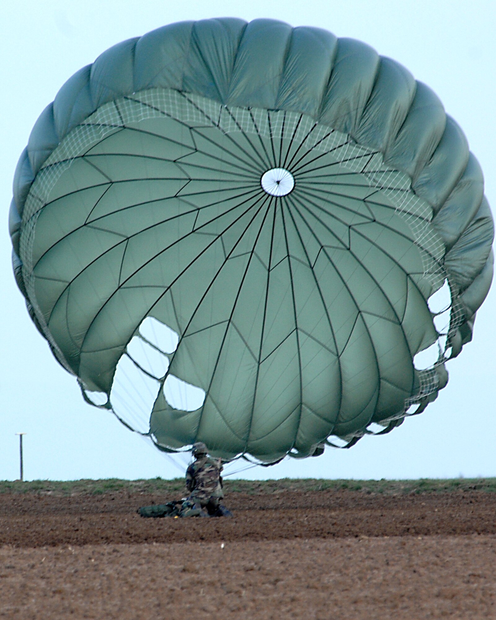 An Airman from the 786th Security Forces, Sembach Annex, Germany reaches the ground March 8 and gathers his parachute after parachuting off the back ramp of a C-130 Hercules during a tactical training exercise over southwestern Germany. (U.S. Air Force photo/Airman Kenny Holston)