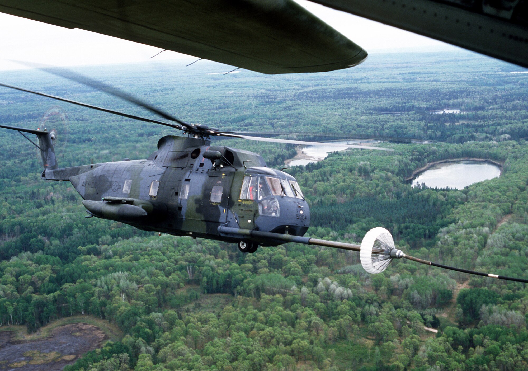 An air-to-air right side view of an HH-3E Jolly Green Giant  helicopter being refueled by an HC-130 Hercules aircraft, in flight, during a reserve rescue exercise. (U.S. Air Force photo/Staff Sgt. Ernest H. Sealing)