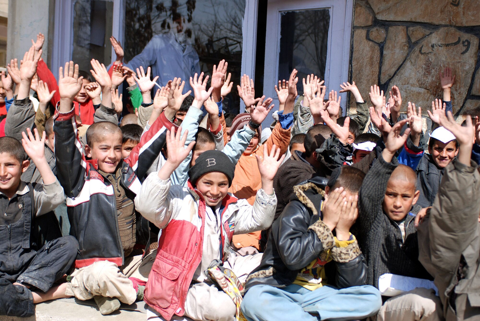 Afghan children from a school in downtown Kabul, Afghanistan., cheer on coalition forces carrying school supplies March 8 into the school yard during a recent community relations trip. Volunteers from the Combined Security Transistion Command were a part of this coalition-sponsored visit. (U.S. Air Force photo/Senior Airman Stacia Zachary)