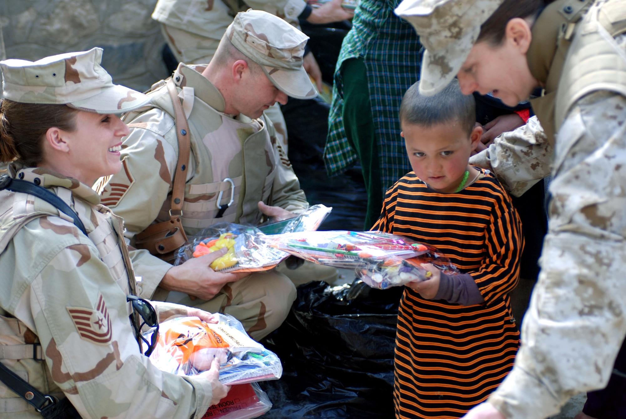 (From left) Tech. Sgt. Shelly Ward, Master Sgt. Shane Enos and Marine Corps Maj. Shawn Haney distribute school supplies to children March 8 at a school in downtown Kabul, Afghanistan. The team from the Combined Security Transition Command were part of a volunteer community relations trip sponsored by coalition forces. (U.S. Air Force photo/Senior Airman Stacia Zachary)