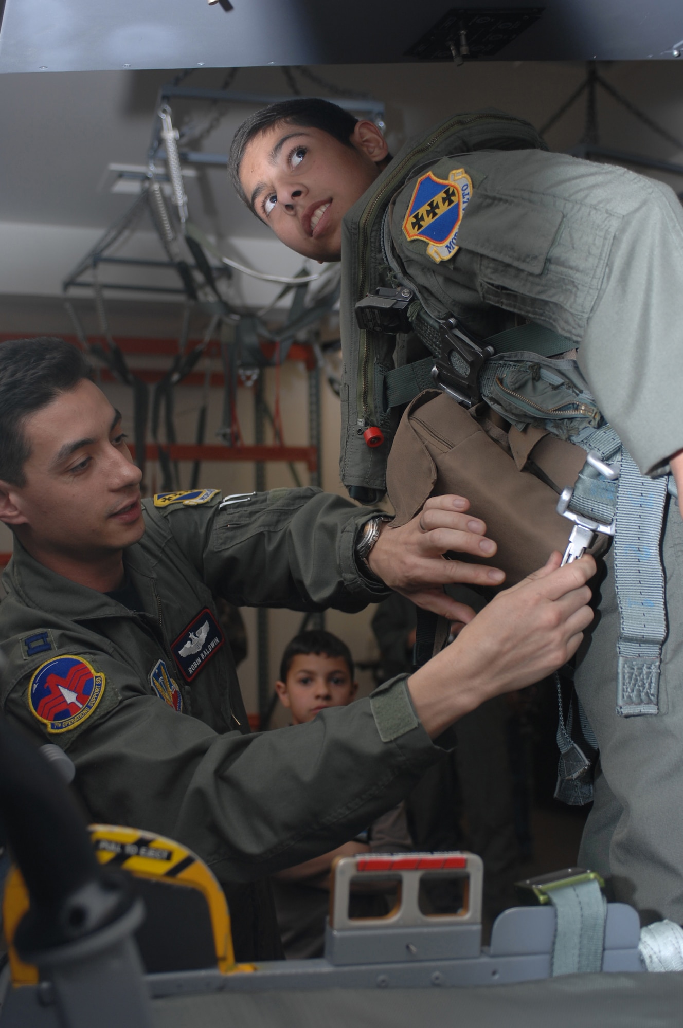 Thirteen-year-old Andrew Crespo is strapped into a B-1 seat ejection simulator here by Capt. Robin Baldwin, 7th Operations Support Squadron, March 7. Andrew has Lukemia and was chosen for Dyess' first "Pilot for a Day" program. (U.S. Air Force photo by Airman 1st Class Domonique Simmons)