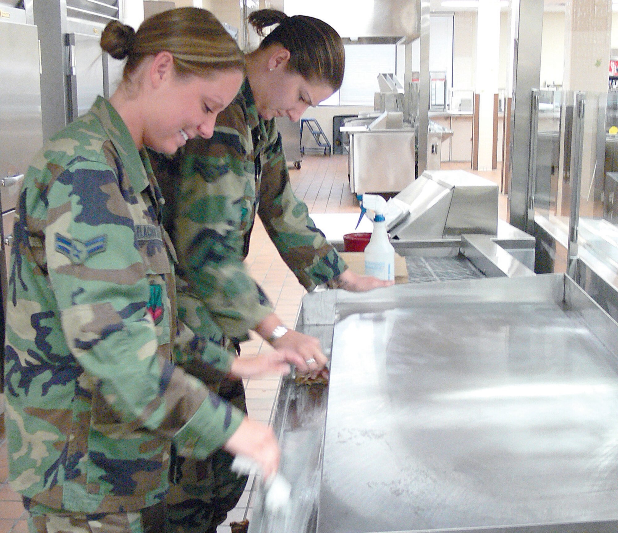 Airmen 1st Class Britney Flachofsky and Tanja Moore, 23rd Services Squadron, clean portions of the new stainless steel serving line March 12 at the Georgia Pines dining facility. Georgia Pines is scheduled to re-open this month after several upgrades that are designed to enhance the facility's overall eating experience. (U.S. Air Force photo by Airman 1st Class Eric Schloeffel) 