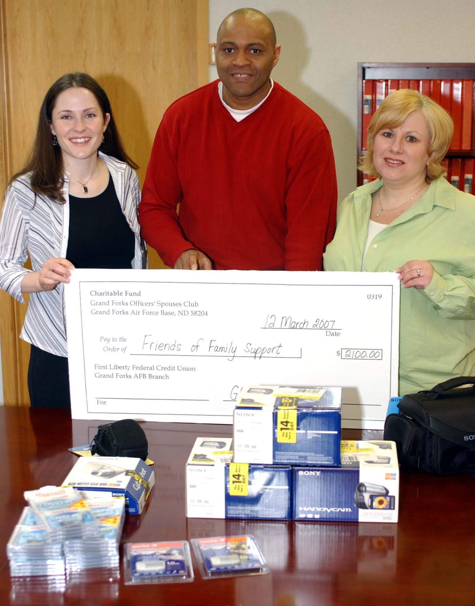 Mrs. Becky Daw (L) and Mrs. Jill Ayres (R) present a check in the amount of $2,100 to Mr. Tom Slaughter to fund purchases of digital video cameras, a digital camera and other equipment for the Airman and Family Readiness Center.  Mrs. Daw and Mrs. Ayres are the first vice-president and president of the Grand Forks Air Force Base Officer's Spouse Club.  The new cameras will be used to tape personal messages for deployed members and their families. (U.S. Air Force photo/Tech. Sgt. Joseph Kapinos)