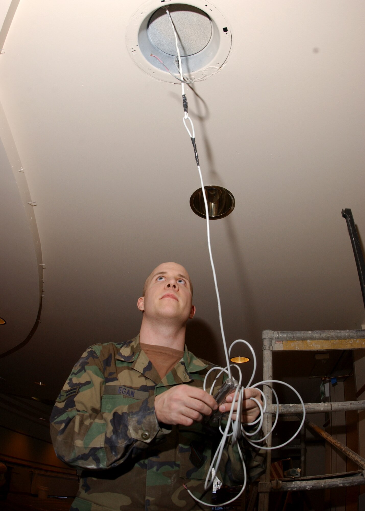 EIELSON AIR FORCE BASE, Alaska -- Airman 1st Class Lance Egan, 354th Communications Squadron, Radio Maintenance, feeds new audio cables through the ceiling to the 8 inch JBL speaker at the Aurora Club on March 13. The Radio Maintenance shop has replaced over 1000 ft of audio cable and has to install a permanent 23 speaker sound system; projected completion time is one week. After this system is installed they will save an estimated 1000 man hours of setup and tear down time every year. (U.S. Air Force photo by Airman 1st Class Jonathan Snyder)