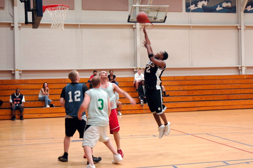 Steve Shelton, 437th Aircraft Maintenance Squadron, shoots the ball as Julio Reyes (right), 437th Services Squadron, Rich Etterling (center), SVS, and Kenneth Travis (left), AMXS, watch for the rebound during the basketball game March 13 at the fitness center.  AMXS defeated SVS 58-31.  (U.S. Air Force photo by Staff Sgt. Marie Cassetty)