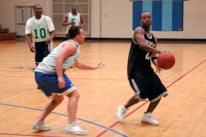 Zach Fivgas, 437th Services Squadron, guards against Steve Shelton, 437th Aircraft Maintenance Squadron, during their basketball game March 13 at the fitness center.  AMXS defeated SVS 58-31.  (U.S. Air Force photo by Staff Sgt. Marie Cassetty)