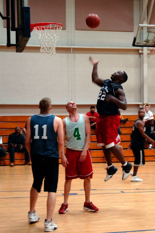 Fredrick Lomas, 437th Aircraft Maintenance Squadron, shoots a jump shot as Yale Akers, AMXS and Julio Reyes, 437th Services Squadron, watch for the rebound during the basketball game March 13 at the fitness center.  AMXS defeated SVS 58-31.  (U.S. Air Force photo by Staff Sgt. Marie Cassetty)