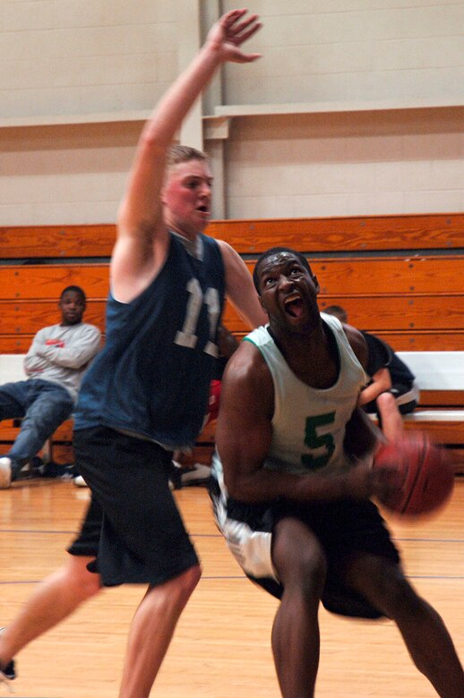 Yale Akers, 437th Aircraft Maintenance Squadron, tries to block a shot by Clinton Coleman, 437th Services Squadron, during the March 13 basketball game at the fitness center.  AMXS defeated SVS 58-31.  (U.S. Air Force photo by Staff Sgt. Marie Cassetty)