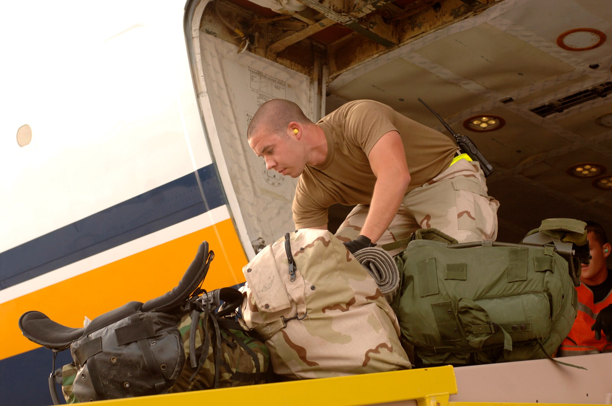 Airman 1st Class Mark Hedge unloads baggage from a commercial aircraft. Airmen from the 8th Expeditionary Air Mobility Squadron processed nearly 257,000 servicemembers, coalition partners and federal contractors for travel in 2006. Airman Hedges is an air transportation specialist with the 8th AEMS. (U.S. Air Force photo/Staff Sgt. David Miller) 