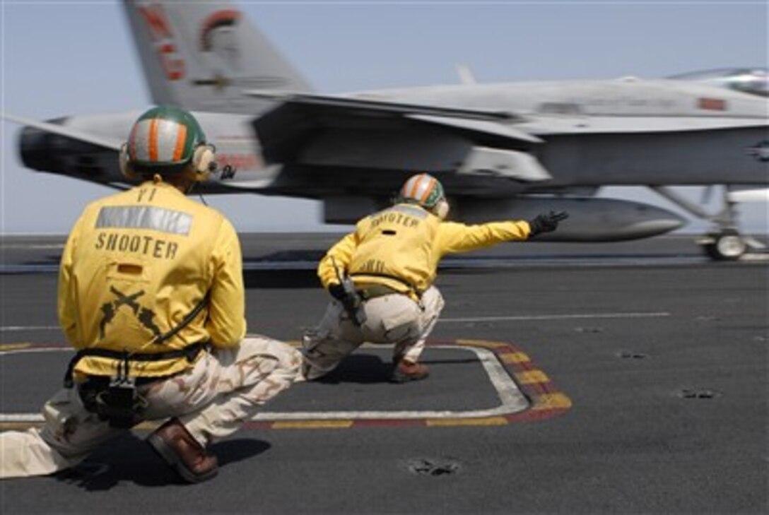 Flight deck officers, referred to as shooters, launch an F/A-18C Hornet assigned the "Argonauts" of Strike Fighter Squadron 146 off the flight deck of Nimitz-class aircraft carrier USS John C. Stennis, March 13, 2007.