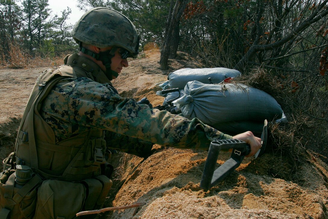 RODRIGUEZ LIVE FIRE COMPLEX, Republic of Korea ? Cpl. Brian D. St. Amour, a fire team leader with Company G, Battalion Landing Team 2nd Battalion, 1st Marine Regiment, improves the camouflage of his fighting hole atop Manchu Hill during area defense training, March 15. After the construction of a fighting hole is complete, the positions must be camouflaged to conceal the Marines within. St. Amour is a Marquette, Mich. native. BLT 2/1 is the ground combat element of the 31st Marine Expeditionary Unit.