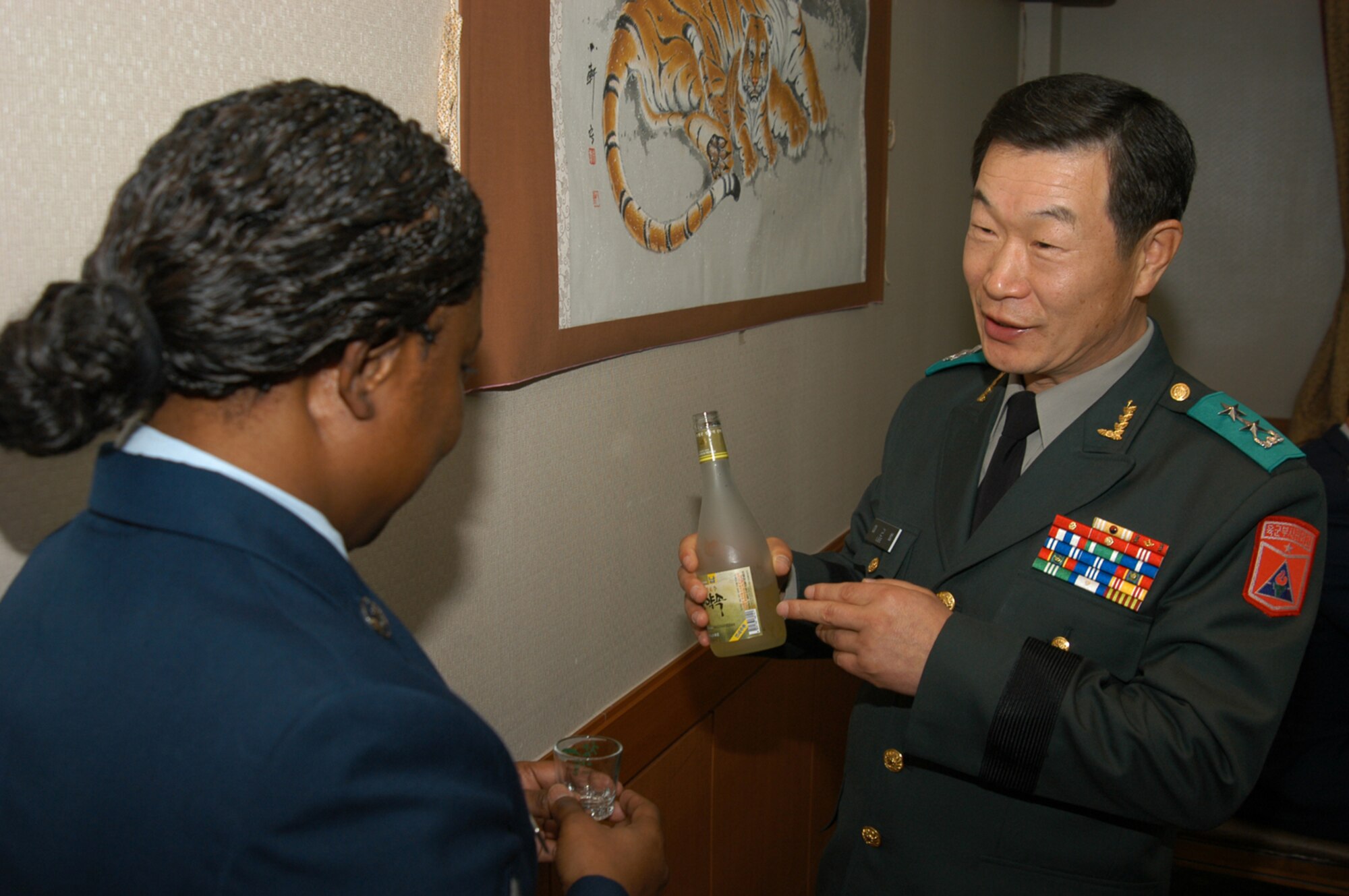 KUNSAN AIR BASE, Republic of Korea March 10, 2007 -- Republic of Korea army Maj. Gen. YiLee, Kun bum, ROK NCO academy commandant, explains the meaning of a bottle of celebatory wine to Tech. Sgt. Christine Williams, 8th Medical Operations Squadron. (Air Force photo/Senior Airman Stephen Collier)                                                                                                                                