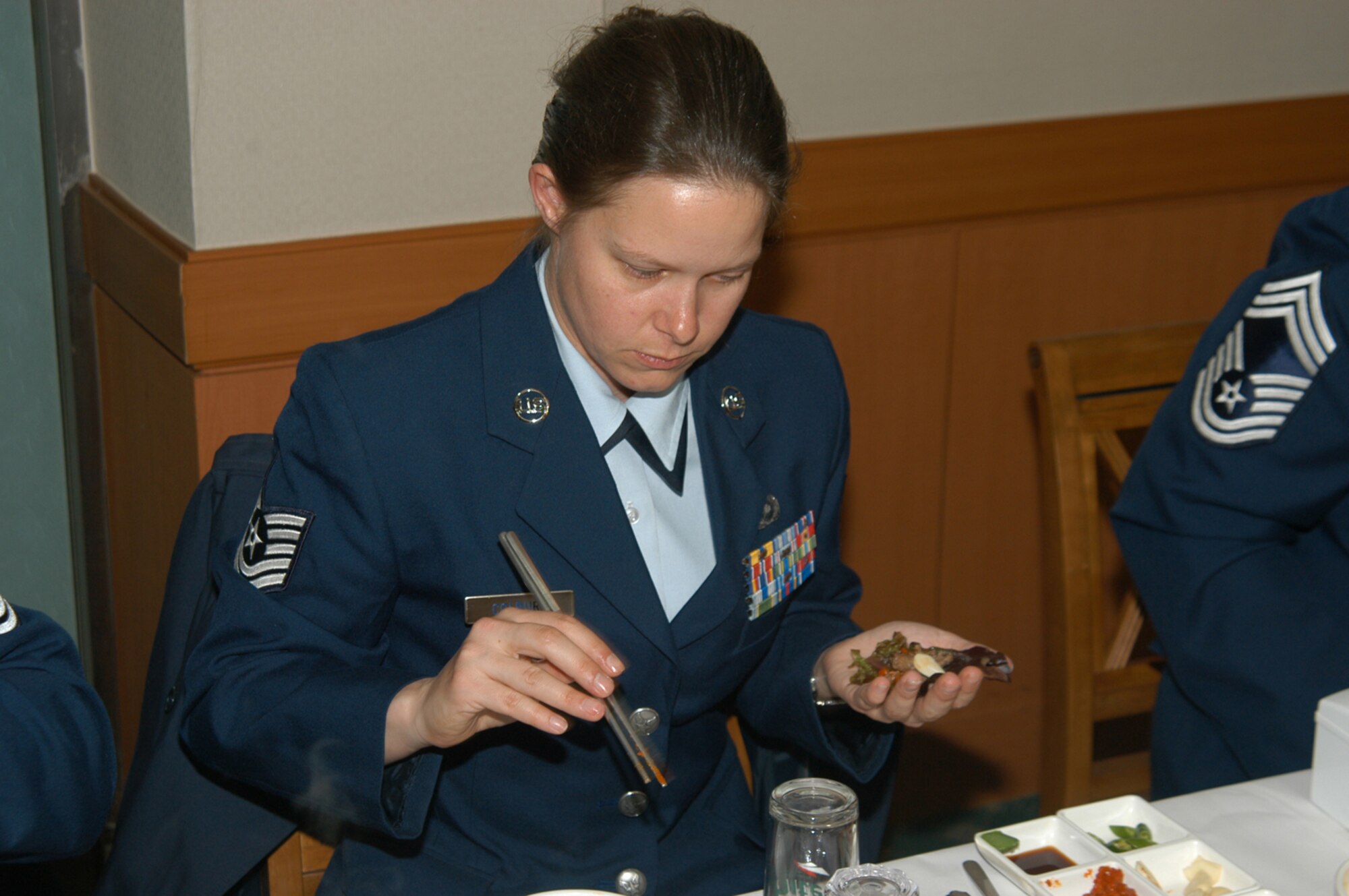 KUNSAN AIR BASE, Republic of Korea March 10, 2007 -- Tech. Sgt. Michelle Colburn learns the inner workings of chopsticks while dining at the Republic of Korea army NCO academy March 10. Five 8th Fighter Wing 'Wolf Pack' members, including Sgt. Colburn, have volunteered to teach up and coming ROK army NCOs conversational English as part of a new program between the academy and Kunsan. (Air Force photo/Senior Airman Stephen Collier)                                                                                                                                                                