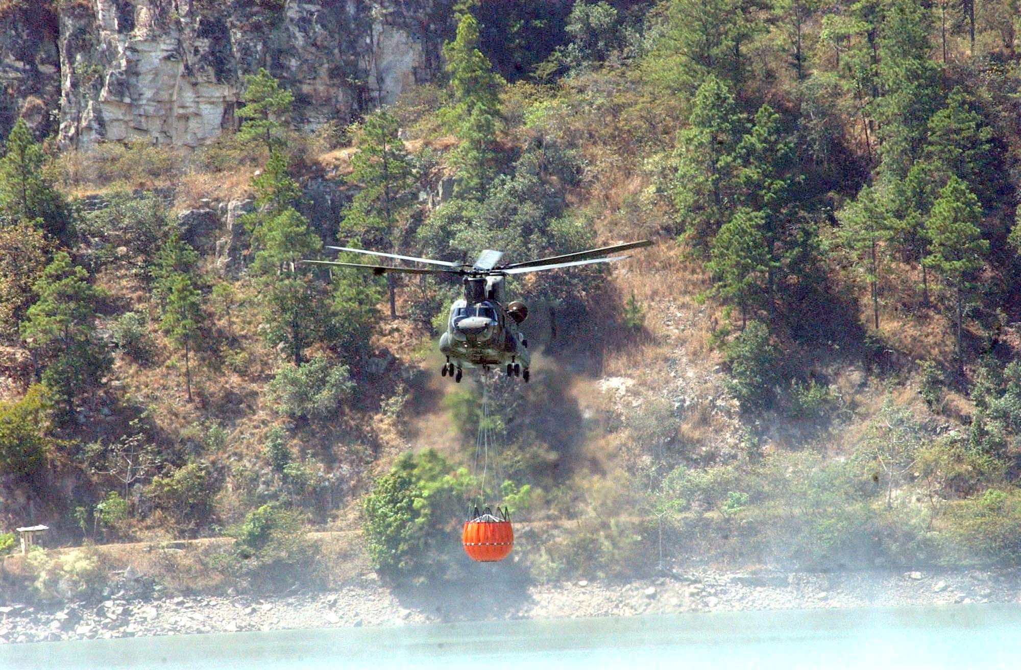 A CH-47 Chinook collects water with a “Bambi Bucket” system during a training mission March 15.  The 2,000-gallon bucket is designed to hang from the helicopter, collect water, and disperse the water at the touch of a button over a fire.  The training took place in small body of water along the Rio del Hombre, near the town of Zambrano, Honduras. (U.S. Air Force photo/Tech. Sgt. Sonny Cohrs)