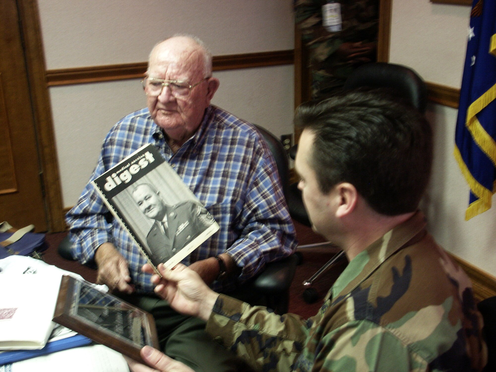 Retired Chief Master Sgt. Ray Smith (left) recalls the occasion back in 1968 when he was chosen as the first medical enlisted force chief as he visited with Chief Master Sgt. Mark Withers, the current top enlisted medical chief, March 7 at Wilford Hall Medical Center, Lackland Air Force Base, Texas.  Chief Withers holds a copy of the Air Force Medical Service Digest from 1968 with Chief Smith's photo on the cover announcing his appointment.  (U.S. Air Force photo/Master Sgt. Kimberly Spencer)