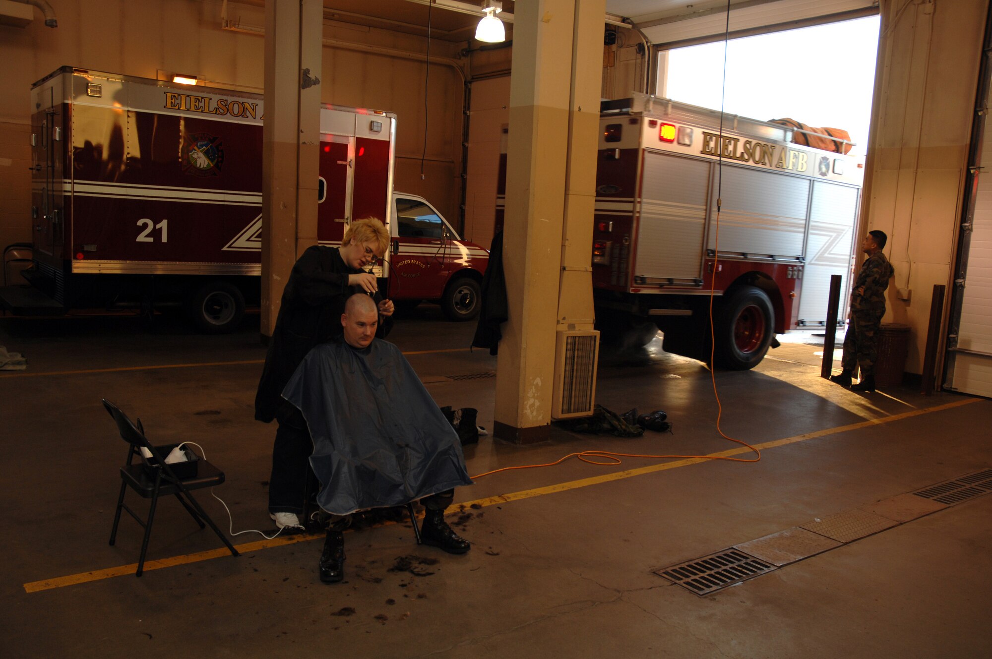 EIELSON AIR FORCE BASE, Alaska --  Staff Sgt. Stephen Tippets, 354th Civil Engineer Squadron B-shift fire fighter, gets his head shaved on March 15 at Fire Station #1 by his wife, Sammantha, while A-shift pulls a rescue truck out of the station in response to a call. Members of the Eielson Fire Fighter Association shaved their heads to raise money for St. Baldricks Foundation which raises funds for children's cancer research.
(U.S. Air Force Photo by Staff Sgt Joshua Strang)