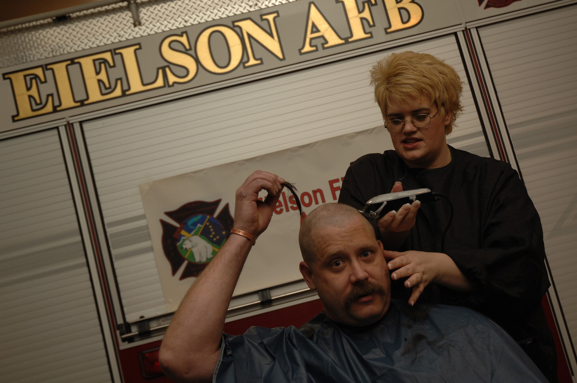 EIELSON AIR FORCE BASE, Alaska -- Mr. Peter Matheis, 354th Civil Engineer Squadron fire fighter station chief, poses with a lock of his hair while getting his head shaved on March 15 at Fire Station #1 by Mrs. Sammantha Tippets, wife of fire fighter Staff Sgt. Stephen Tippets,. Members of the Eielson Fire Fighter Association shaved their heads to raise money for St. Baldricks Foundation which raises funds for childrens cancer research.
(U.S. Air Force Photo by Staff Sgt Joshua Strang)