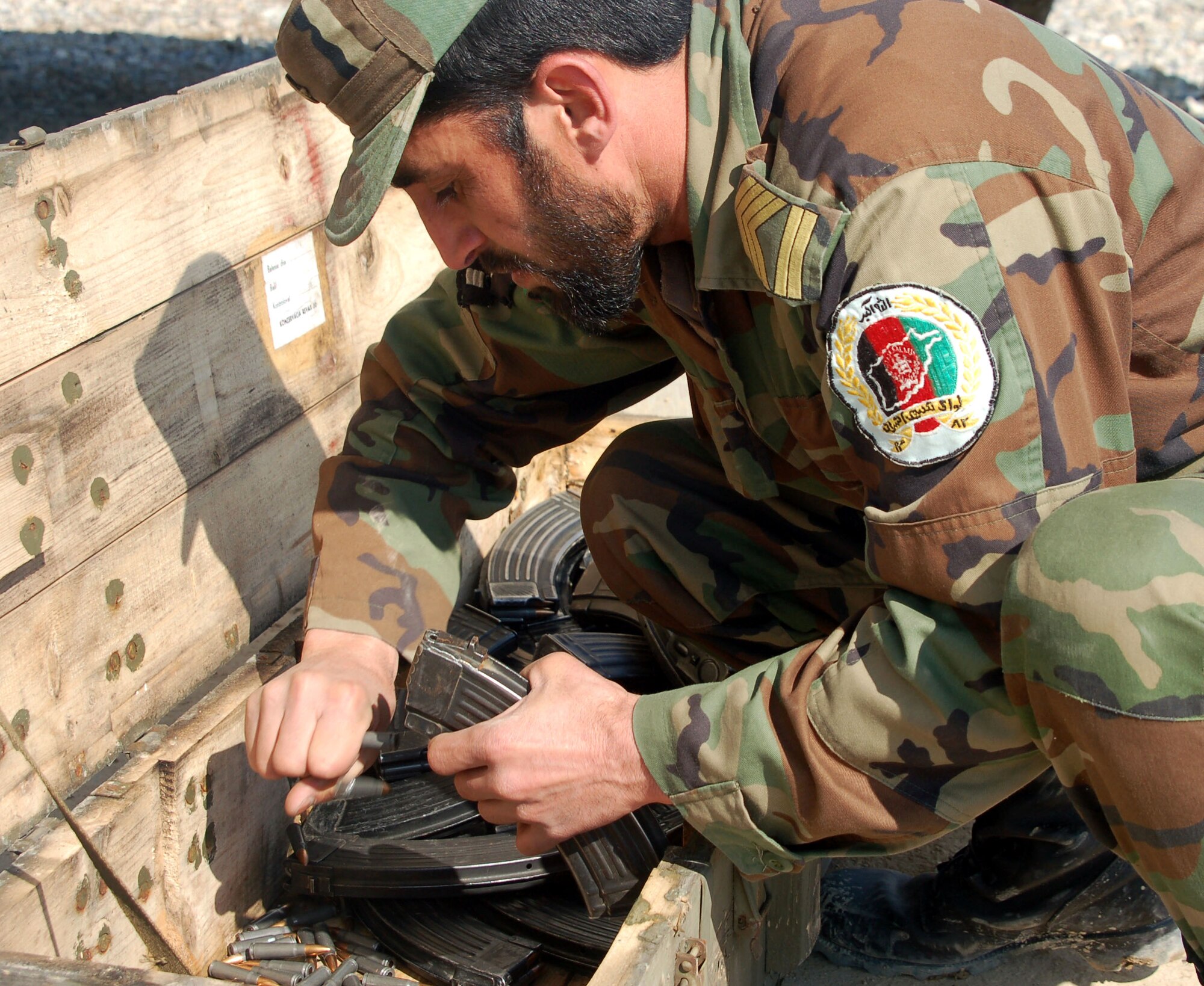 An Afghan National Army soldier removes the extra ammunition from AK-47 magazines after target practice is concluded. A battalion of ANA soldiers underwent long-rifle training March 14 at the Kabul Military Training Center.  (U.S. Air Force photo/Senior Airman Stacia Zachary)