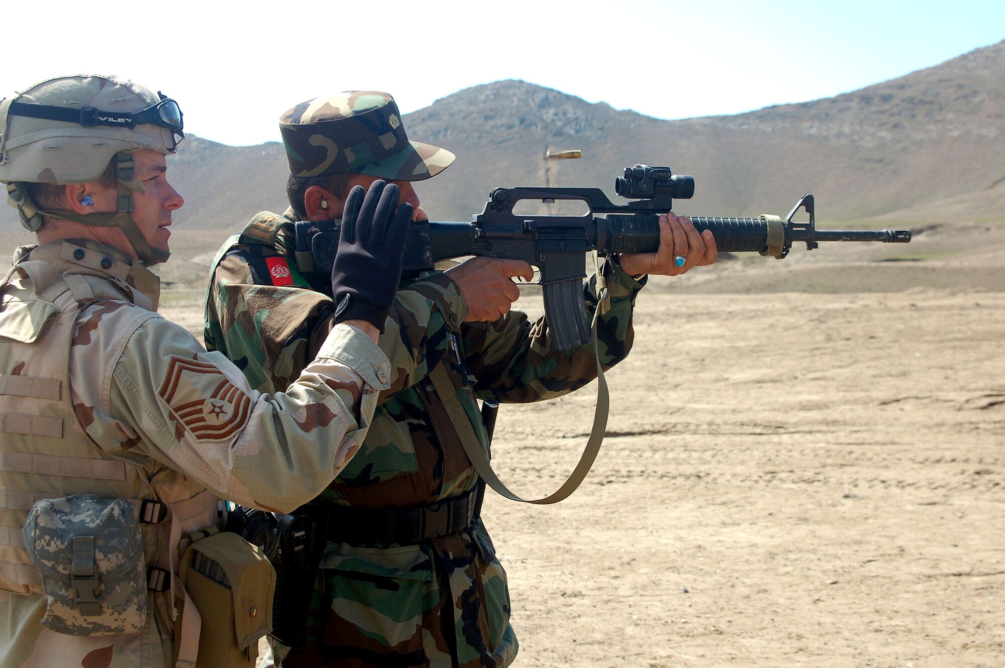 Senior Master Sgt. Robert Spaulding shows Afghan National Army Capt. Abdul Rahman the mechanics of an M-16 March 14 and how to view the target through the optical scope.  Captain Rahman, 1st Company military police commander, shot all 30 rounds within the target.  Sergeant Spaulding, the garrison sergeant major for the Training Assistance Group, is deployed from the 4th Logistics Readiness Squadron at Seymour-Johnson Air Force Base, N.C.  (U.S. Air Force photo/Senior Airman Stacia Zachary)