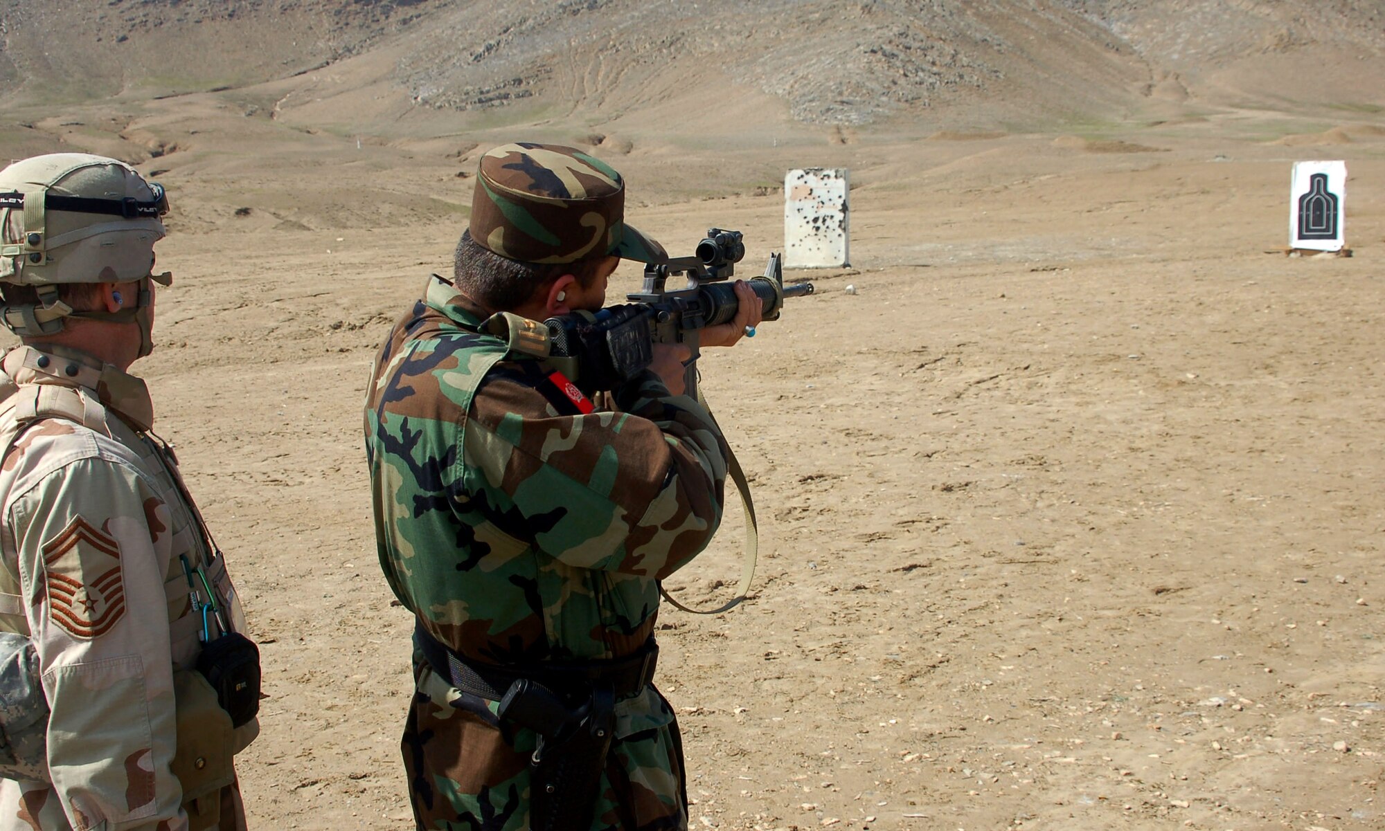Senior Master Sgt. Robert Spaulding shows Afghan National Army Capt. Abdul Rahman the mechanics of an M-16 March 14 and how to view the target through the optical scope.  Captain Rahman, 1st Company military police commander, shot all 30 rounds within the target.  Sergeant Spaulding, the garrison sergeant major for the Training Assistance Group, is deployed from the 4th Logistics Readiness Squadron at Seymour-Johnson Air Force Base, N.C.  (U.S. Air Force photo/Senior Airman Stacia Zachary)
